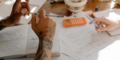 Students collaborate over study notes, textbooks, and a calculator in a casual setting.